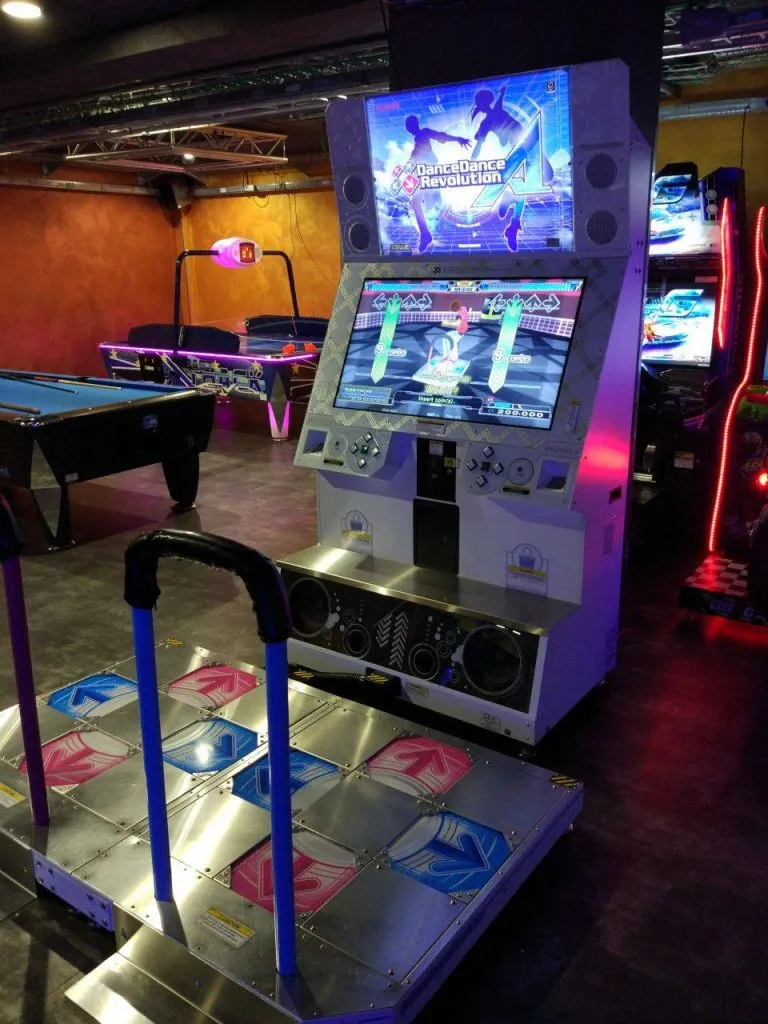 a standard DanceDanceRevolution A White cabinet, pictured in a dark games room.