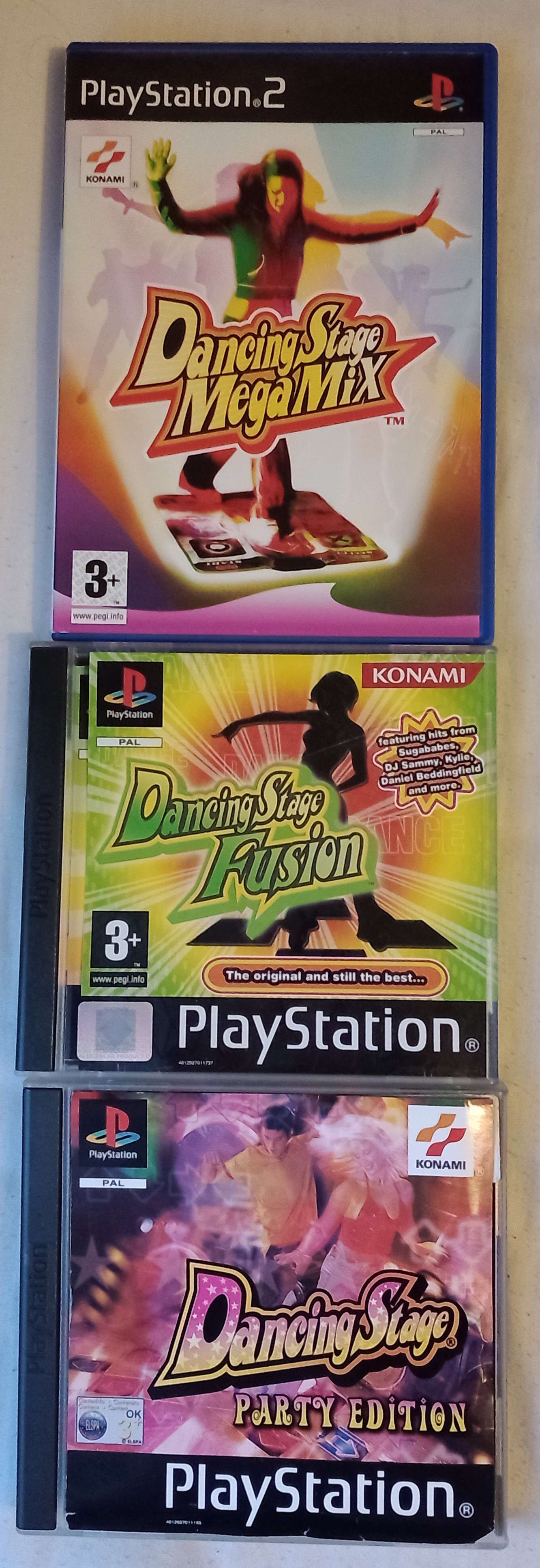 three dancing stage games lined up. in order: dancing stage megamix for the PS2, dancing stage party edition for PS1, and dancing stage fusion for PS1.